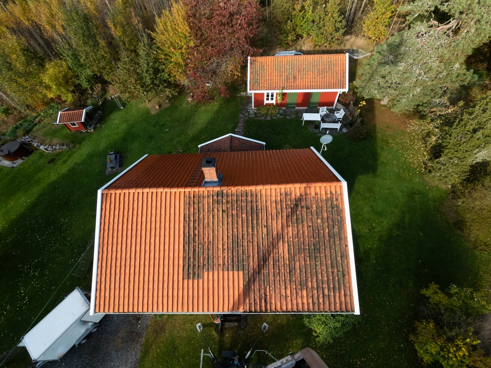 power washing house from above view. trees and shed in the back